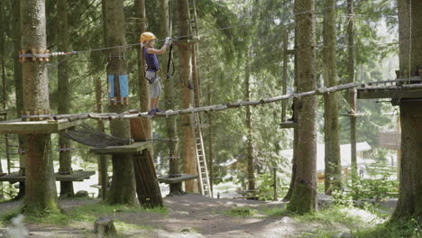 Little-girl-crosses-a-tibetan-bridge-in-adventure-park-in-italian-Alps-4K