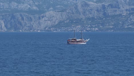 Kleine-Fähre-überquert-Die-Mitte-Des-Blauen-Meeres-Am-Nahe-Gelegenen-Berg