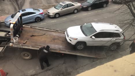 Coche-Estacionado-Ilegalmente-Siendo-Remolcado-Fuera-De-La-Calle-De-La-Ciudad-Con-Un-Oficial-De-Policía-Mirando