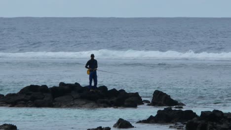 Un-Pescador-Tirando-La-Caña-De-Unas-Rocas-En-El-Agua