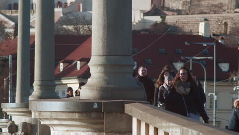 Pedestrians-and-tram-cross-conic-Prague-bridge-on-cold-day,-slow-mo