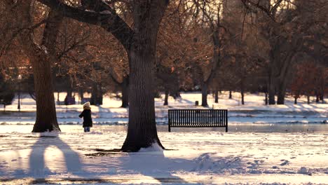 Niño-Pequeño-Jugando-Con-Nieve-En-El-Parque-Contra-Un-Fondo-De-Luz-Cálida