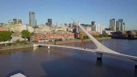 Cinematic-aerial-shot-rising-over-Puente-de-la-Mujer,-revealing-downtown-Buenos-Aires