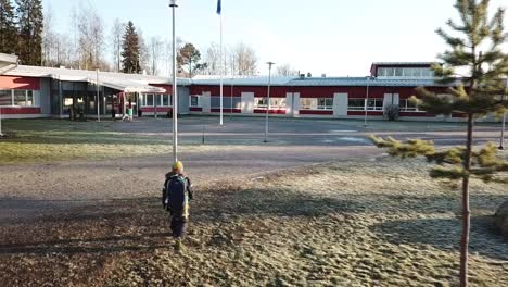 Colegial-Con-Mochila-Caminando-A-La-Escuela-En-Un-Clima-Frío-Y-Helado,-Rastreando-Tomas-Aéreas