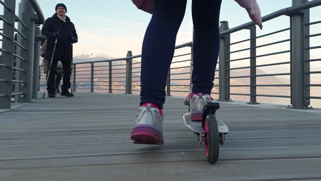 Low-angle-tracking-girl-child-kick-riding-scooter-on-bend