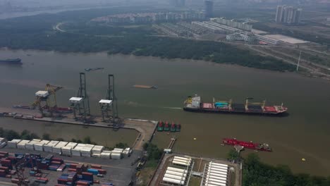 Vista-Aérea-Del-Río-Saigón-Con-La-Instalación-Portuaria-De-Aguas-Profundas,-El-Transporte-Marítimo,-Los-Humedales-Y-Elementos-Del-Horizonte-De-La-Ciudad-En-Un-Día-De-Alta-Contaminación-Del-Aire