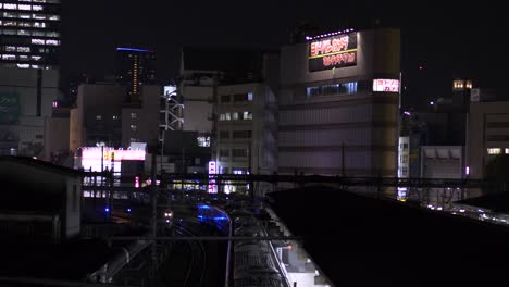 La-Estación-De-Ueno-Y-Los-Edificios-Circundantes-Por-La-Noche-Vistos-Desde-Un-Puente-Peatonal,-Con-Vistas-A-Las-Vías-Y-Los-Trenes-Que-Pasan