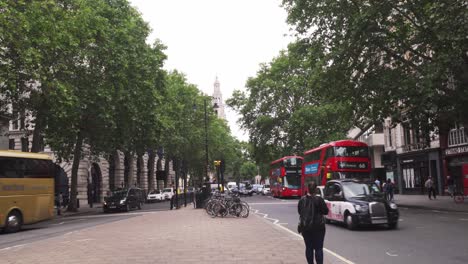 Traffic-in-street-of-London,-cars,-red-double-decker-buses-and-few-people,-typical-day