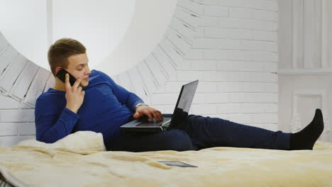 Young-Man-Casually-Using-a-Teléfono-and-Laptop