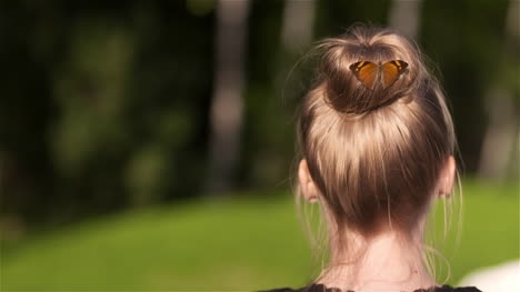 Handheld-Shot-Of-Butterfly-On-Bun-Of-Woman-At-Park
