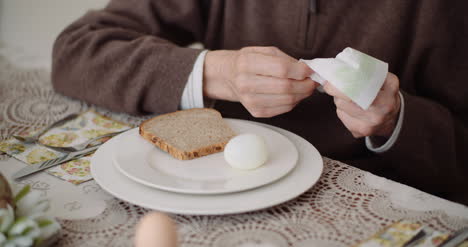 Midsection-Of-Man-Wiping-Hand-With-Tissue-Paper-Before-Having-Bread-And-Egg-At-Table
