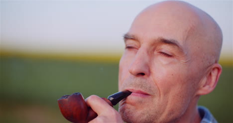 Contented-Bald-Farmer-Smoking-His-Pipe-On-Field-2