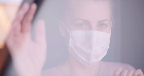 Nahaufnahme-Porträt-Einer-Frau-Mit-Maske,-Die-Während-Des-Ausbruchs-Des-Coronavirus-Durch-Das-Fenster-Gesehen-Wird