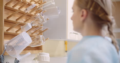 Handheld-Shot-Of-Female-Scientist-Keeping-Glass-Beaker-On-Wooden-Rack-In-Laboratory
