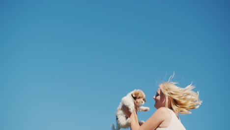 Woman-Jumping-With-Puppy-Against-Blue-Sky