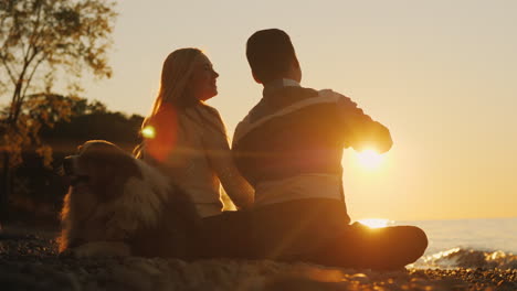 Glückliches-Paar-Und-Hund-Bei-Sonnenuntergang