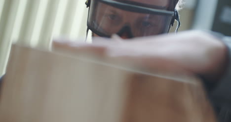 Modern-Carpenter-In-Protective-Glasses-Examining-Wood