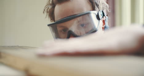 Carpenter-In-Protective-Glasses-Checking-Wooden-Board-