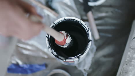 Person-Dipping-Stick-In-Black-Paint-Can