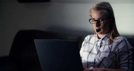 Female-Entrepreneur-Using-Laptop-While-Talking-On-Headset-In-Office