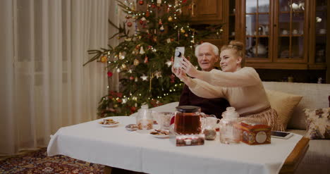 Cheerful-Woman-Taking-Selfie-With-Grandfather-During-Christmas
