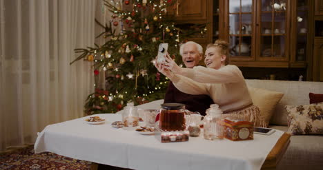 Cheerful-Woman-Taking-Selfie-With-Grandfather-During-Christmas-1
