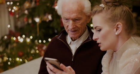 Abuelo-De-Enseñanza-Femenina-Para-Usar-El-Teléfono-Celular-En-Navidad