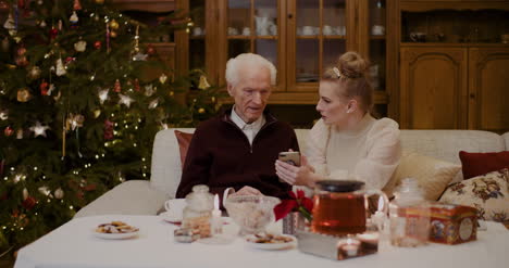 Frau-Lehrt-Großvater,-Smartphone-Zu-Weihnachten-Zu-Benutzen