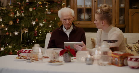 Grandfather-Talking-While-Granddaughter-Holding-Digital-Tablet-3