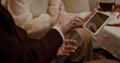 Granddaughter-And-Grandfather-Discussing-Over-Digital-Tablet-At-Home