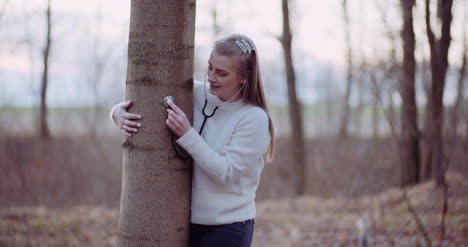 Woman-Uses-A-Stethoscope-And-Examines-A-Tree-In-The-Forest-4