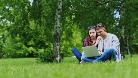 Friends-Of-Man-And-Woman-Sitting-On-The-Grass-In-The-Park-Enjoy-A-Laptop-Hd-Video