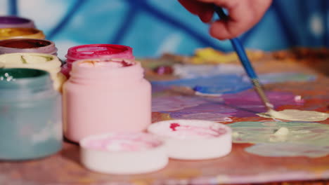 Handmaler-Künstler-Mischt-Farbe-In-Der-Nähe-Steht-Ein-Glas-Farbe