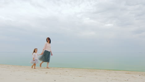 Mother-And-Daughter-Walking-Slowly-Along-The-Seashore
