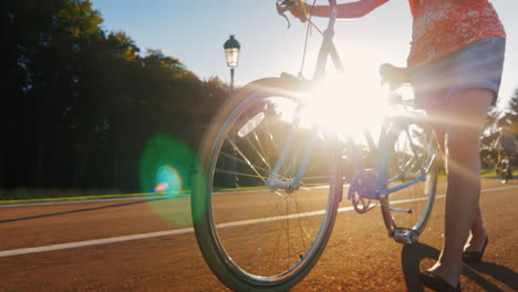 Eine-Frau-Führt-Ein-Fahrrad-Auf-Dem-Bild-Sieht-Man-Die-Beine-Und-Das-Rad-Die-Sonnenstrahlen-Scheinen-Durch