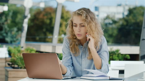 Attraktive-Geschäftsfrau,-Die-Telefoniert,-Sitzt-In-Einem-Café-Auf-Der-Terrasse-Und-Arbeitet-Mit-Einem-Laptop