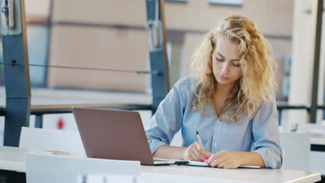 Attractive-Young-Woman-Working-On-The-Site-In-Summer-Kaye-Uses-Laptop-Takes-Notes-In-A-Notebook