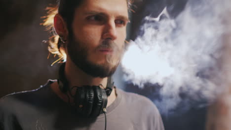 Young-Hipster-Man-Smokes-An-Electronic-Cigarette-Effectively-Produces-Steam-In-A-Beam-Of-Light-Slow-