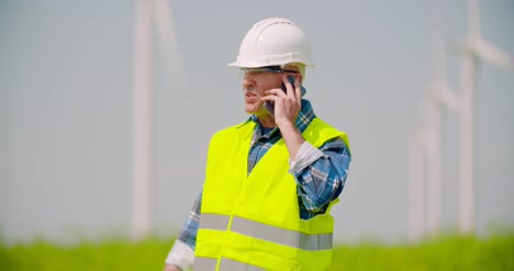 Wütender-Ingenieur,-Der-Am-Handy-Gegen-Windmühlenfarm-Spricht