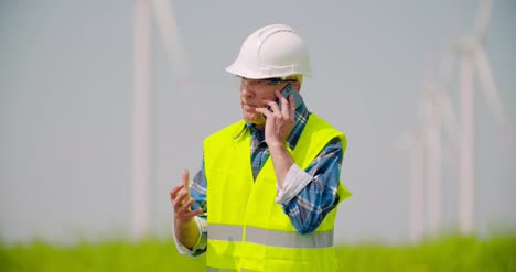 Angry-Engineer-Talking-On-Mobile-Phone-Against-Windmills-Farm-6