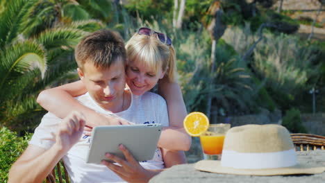 Ein-Ehepaar-Mit-Einem-Tablet-Obschaetsya-Hat-Ein-Video,-Das-Vor-Dem-Hintergrund-Von-In-Die-Kamera-Lächelt