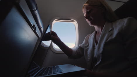 Frau-öffnet-Laptop-Im-Flugzeuggeschäftsreisekonzept