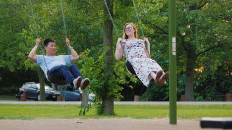 Multi-Ethnic-Couple---Asian-Man-And-Pregnant-Caucasian-Woman-Ride-On-A-Swing-Happy-Young-Family