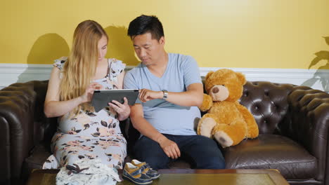 Young-Multi-Ethnic-Couple-Orders-Clothes-For-An-Unborn-Baby-Use-A-Tablet