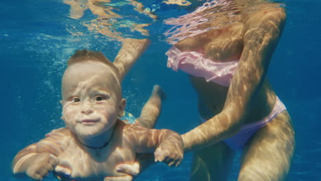 Der-Baby-Boy-Taucht-Im-Pool-Unterwasser-Video-Mama-Unterstützt-Ihn-Vorsichtig