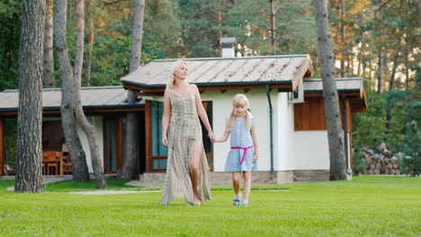 A-Young-Mother-And-Daughter-Are-Walking-Around-The-Lawn-Near-Their-House-Slow-Motion-Video