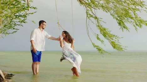 A-Young-Man-Is-Rolling-His-Girl-On-A-Swing-Against-The-Background-Of-The-Sea-In-The-Rain-Romance-And