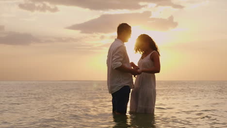 Junges-Verliebtes-Paar,-Das-Bei-Sonnenuntergang-Im-Meer-Steht-Und-Sich-HD-Video-Ansieht