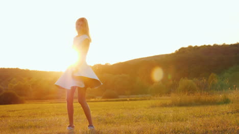 Junge-Frau-In-Einem-Leichten-Kleid-Wirbelt-Auf-Einem-Feld-In-Den-Strahlen-Eines-Sonnenuntergangs-Zeitlupenvideos