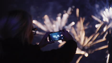 Eine-Frau-Bewundert-Das-Feuerwerk-Am-Nachthimmel-Mach-Fotos-Mit-Deinem-Smartphone